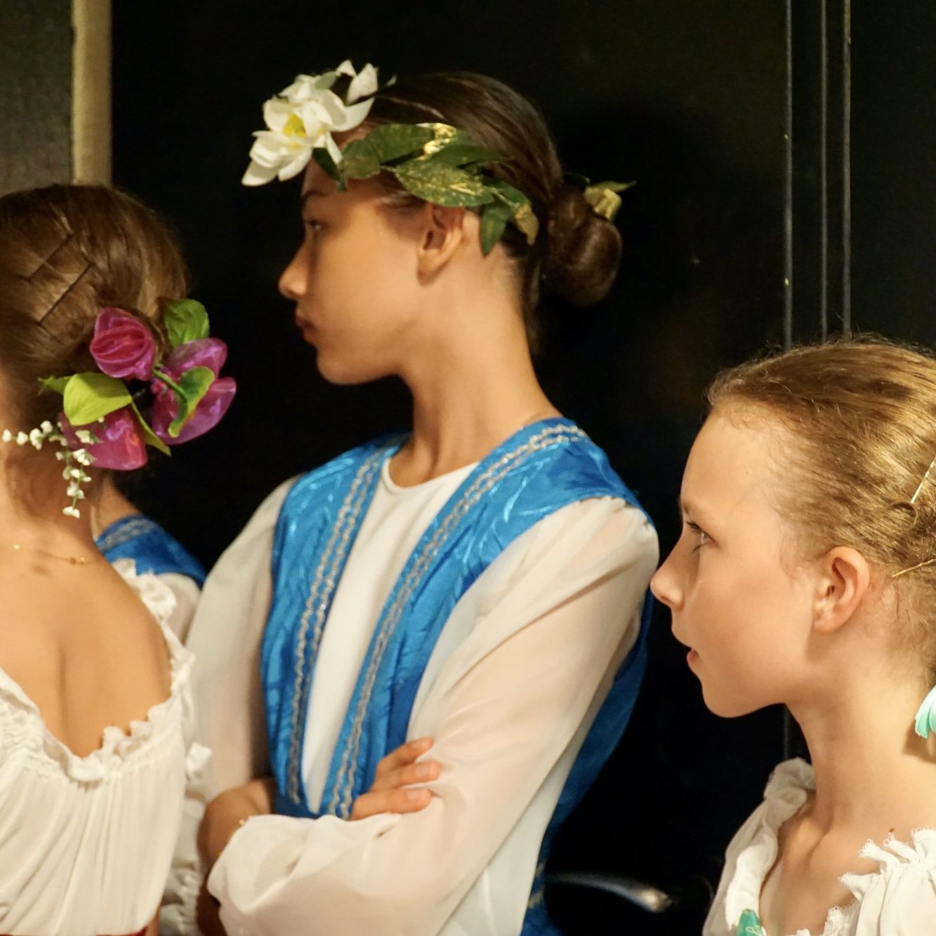 3 Kinder warten im Kostüm vor dem Auftritt im Backstage und wirken konzentriert.
